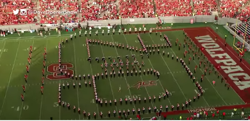Overhead view of the marching band forming the NC State block "S" logo