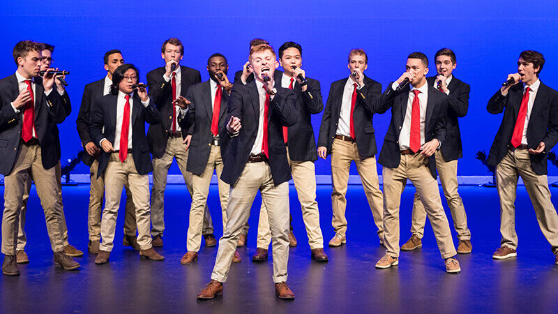 Image of male students in matching outfits singing a cappella.