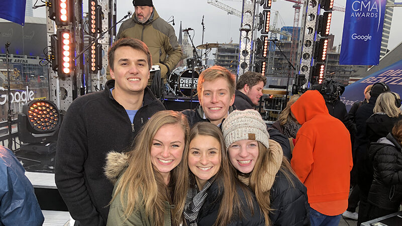 A group of students pose together in Nashville with a concert stage in the background.