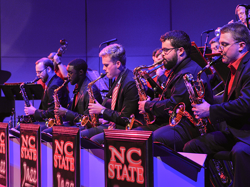 Photo of the saxophone section of the jazz orchestra performing during a concert.
