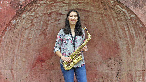 Image of a student holding a saxophone and smiling.