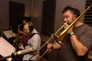 Trombonist performs in a recording studio.