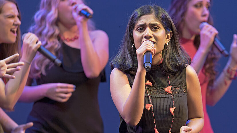 Image of a girl singing with other girls singing behind her.