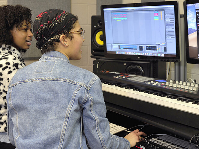 Two girls work on a digital audio workstation computer.
