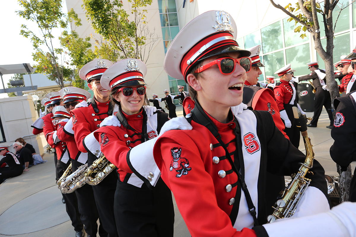 Image of marching band students in a conga line with big smiles.