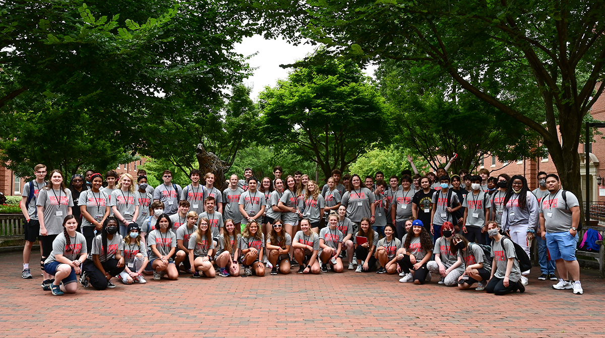 Large group of high school students posing together outdoors during summer music camp.
