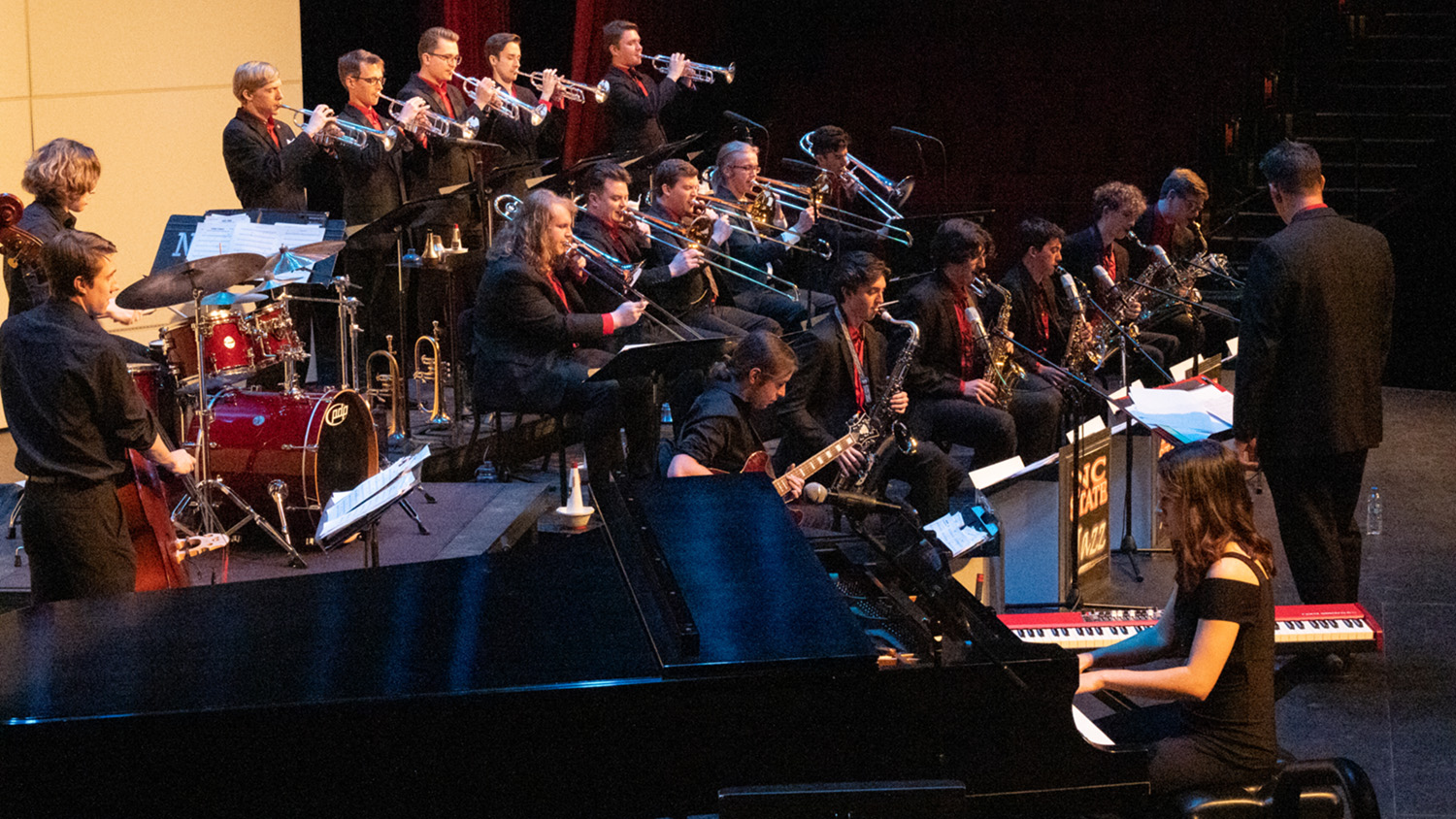 Musicians perform on risers during a jazz orchestra concert.