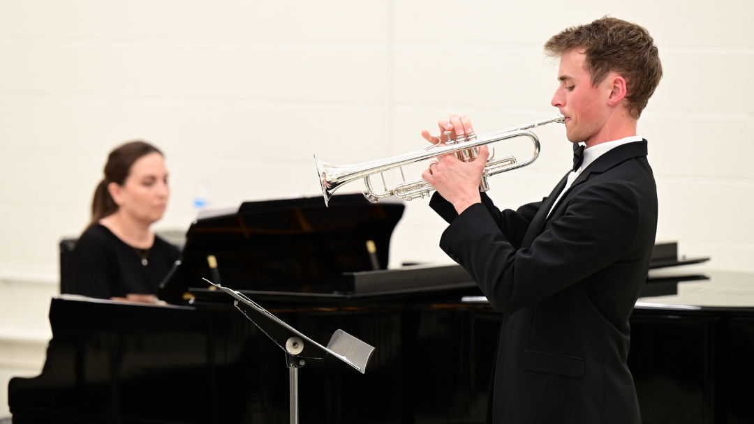 Student plays a trumpet with a pianist providing accompaniment.
