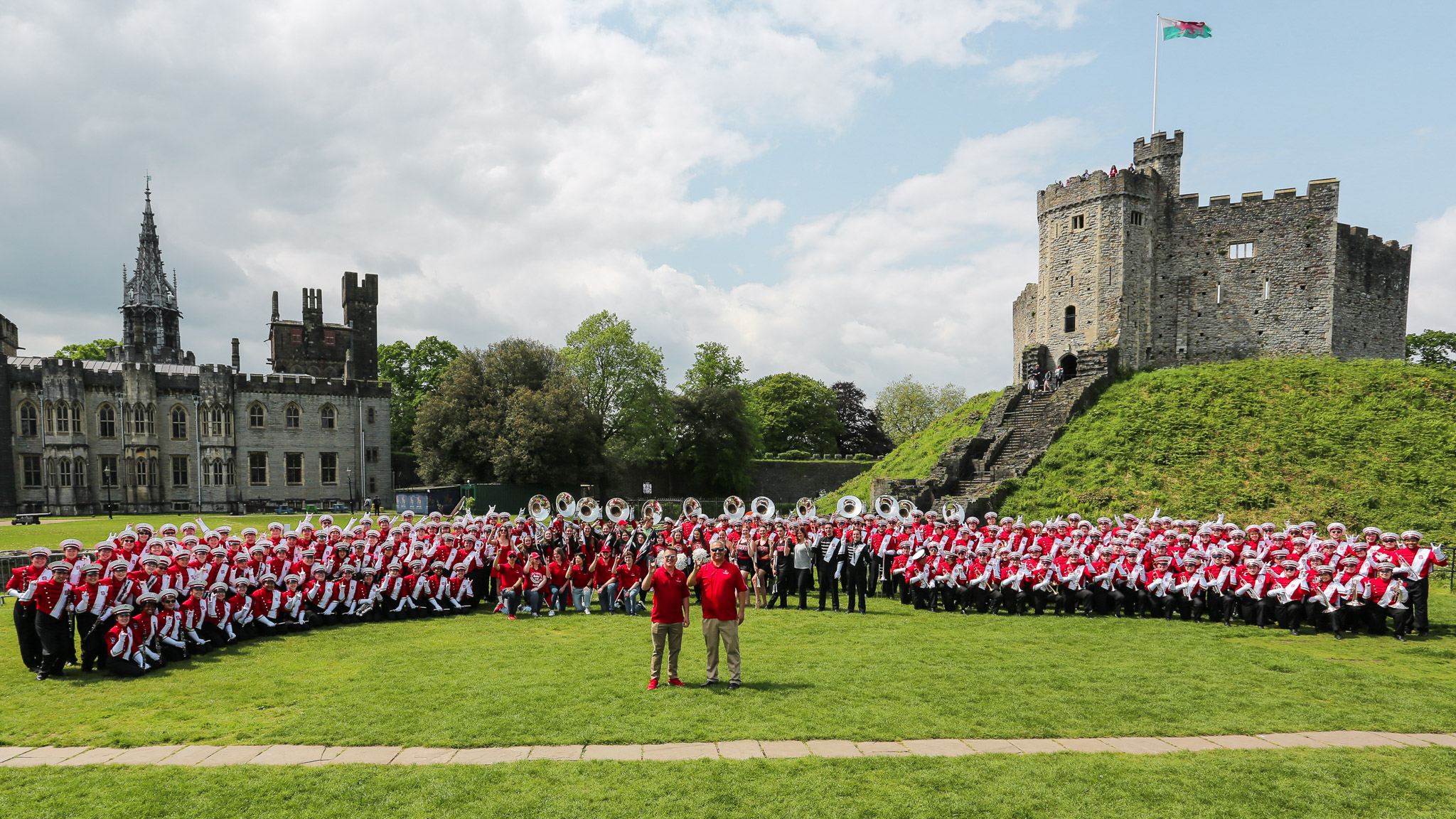 Two band directors stand with their marching band of about 250 students in front of the welsh Cardiff Castle.