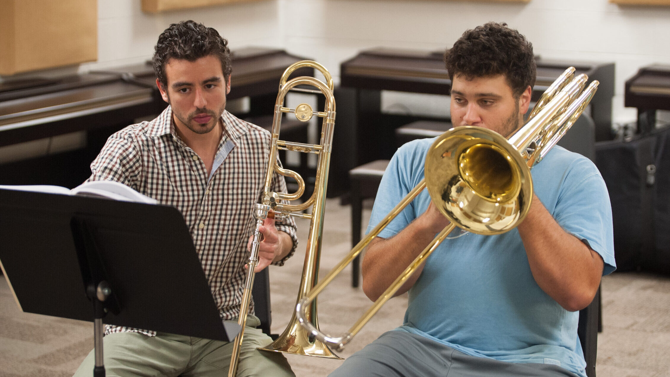 A trombone instructor assists their student during a lesson.