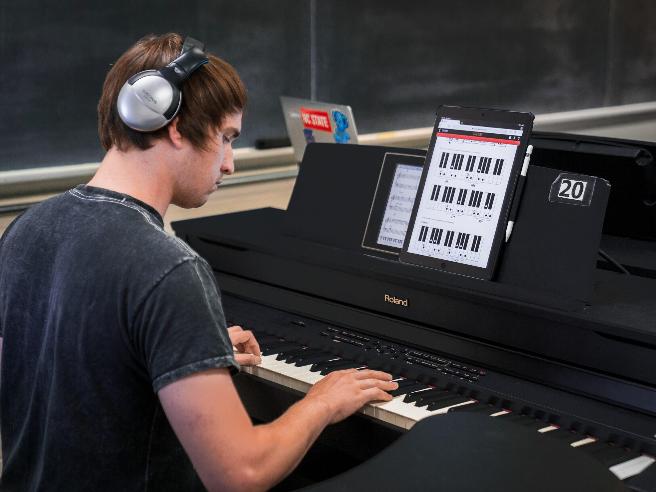 Photo of a student in Class Piano I playing a keyboard while looking at a tablet screen.