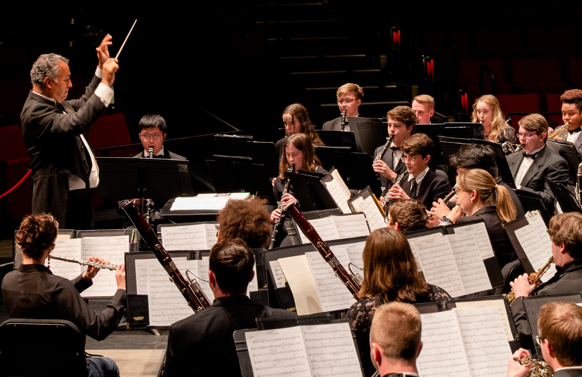 conducter leads a student wind ensemble during a concert performance.